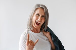 Grey senior woman gesturing while posing with denim jacket isolated over white background